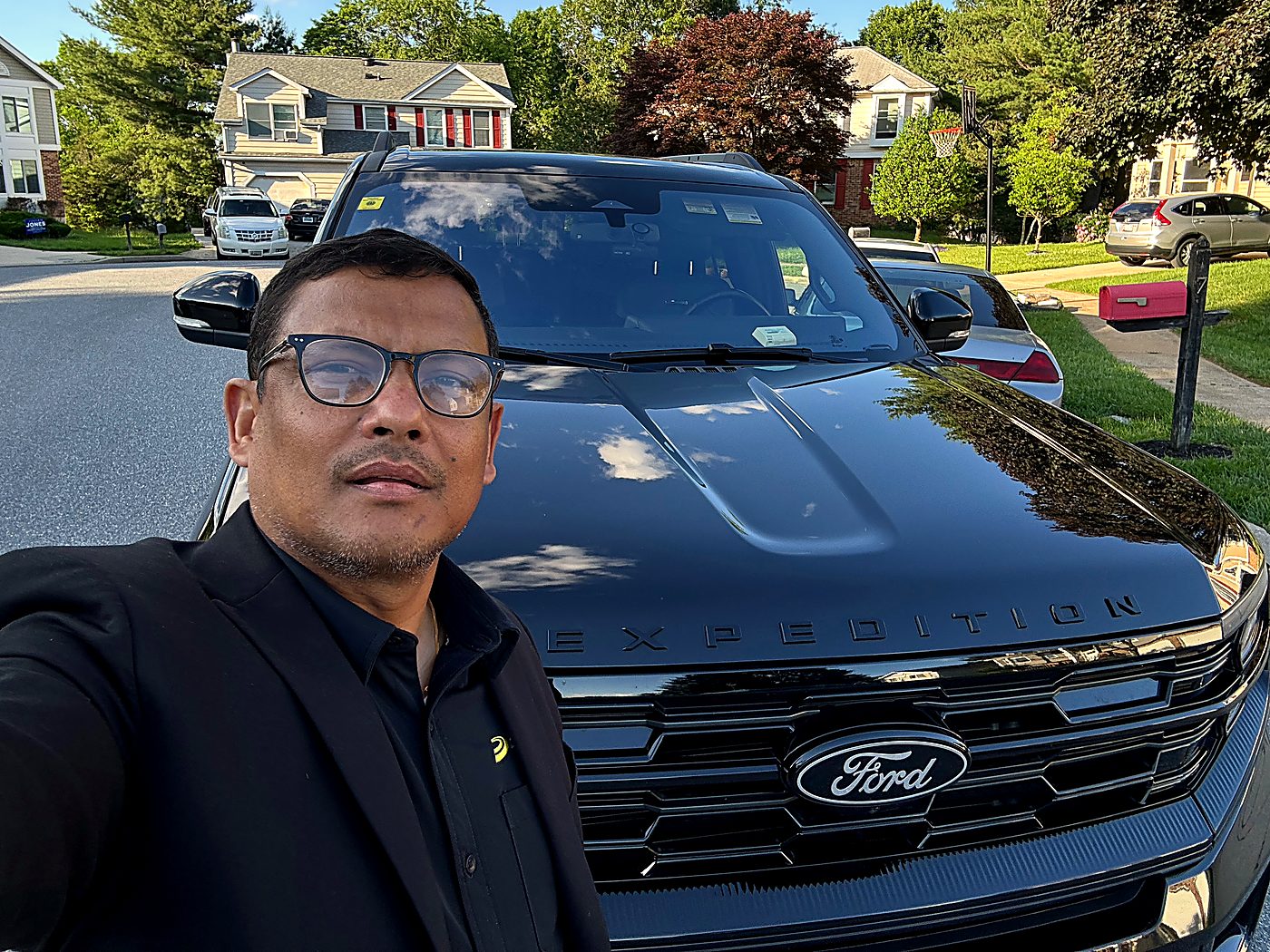 Anil Godar standing beside the black Ford Expedition MAX he drives